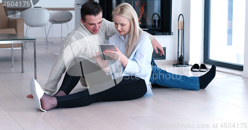 Image of Young Couple using digital tablet on the floor