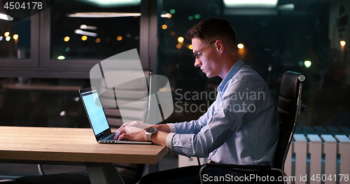 Image of man working on laptop in dark office