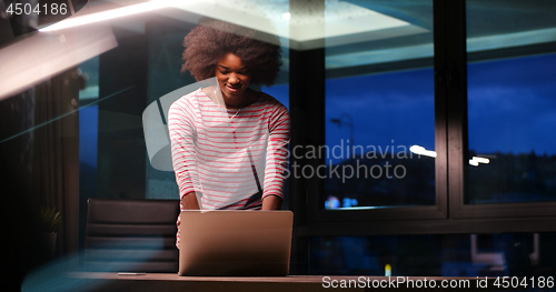Image of black businesswoman using a laptop in night startup office
