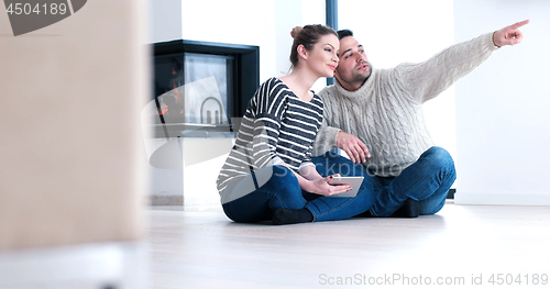 Image of Young Couple using digital tablet on the floor