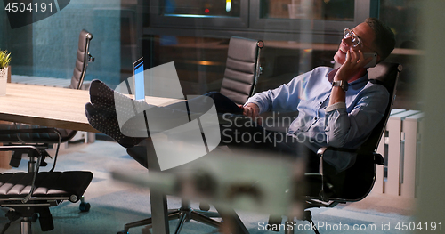 Image of businessman sitting with legs on desk at office