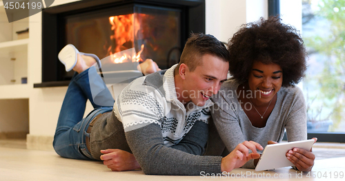 Image of multiethnic couple using tablet computer on the floor