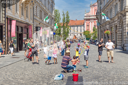 Image of Urban street artist performing a soap bubble show for children in medieval city center of Slovenian capital Ljubljana