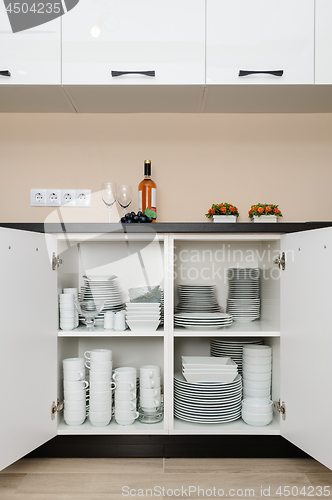Image of Dishware storage cabinet with plates and cups inside