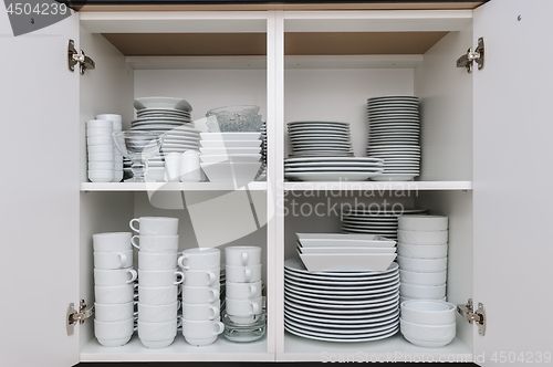 Image of Dishware storage cabinet with plates and cups inside