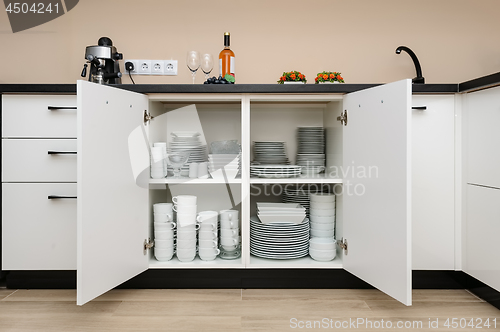 Image of Dishware storage cabinet with plates and cups inside