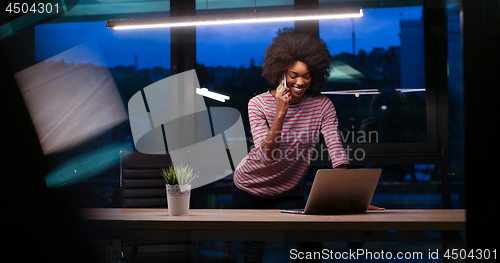 Image of black businesswoman using a laptop in night startup office