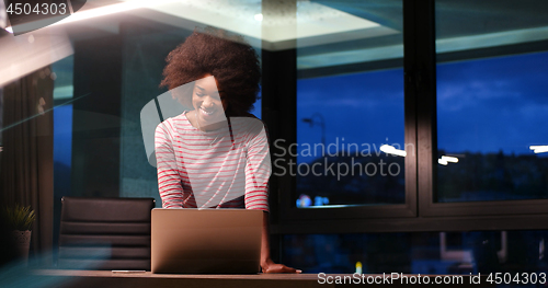 Image of black businesswoman using a laptop in night startup office