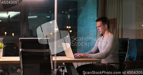 Image of man working on laptop in dark office