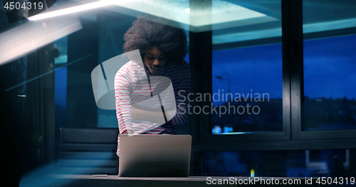 Image of black businesswoman using a laptop in night startup office