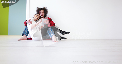 Image of Young Couple using digital tablet on the floor