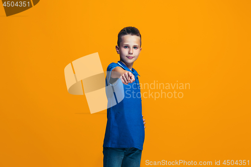 Image of The happy teen boy pointing to you, half length closeup portrait on orange background.