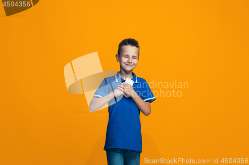 Image of The happy teen boy standing and smiling against orange background.