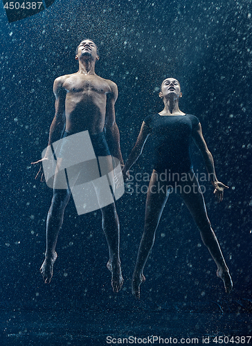 Image of Young couple of ballet dancers dancing unde rwater drops