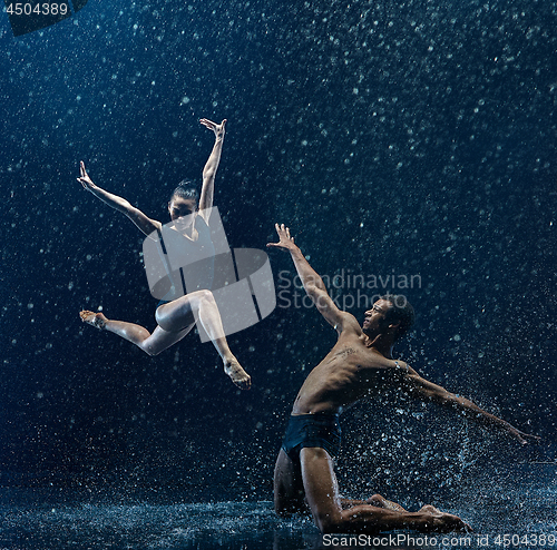 Image of Young couple of ballet dancers dancing unde rwater drops