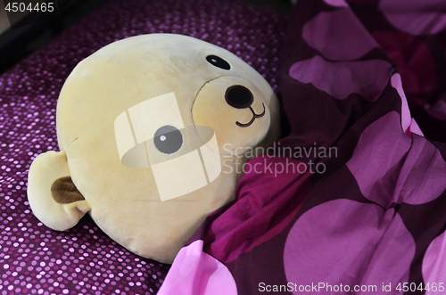 Image of Bear doll sleeping on the purple bed 