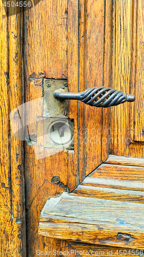 Image of Vintage yellow wooden door with decorative handle and keyhole