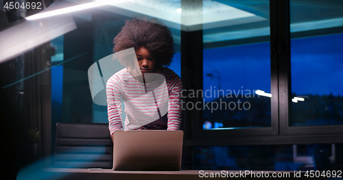 Image of black businesswoman using a laptop in night startup office