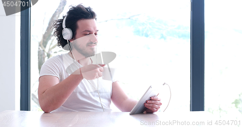 Image of young man listenig music on tablet at home