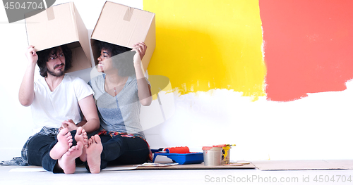 Image of young multiethnic couple playing with cardboard boxes