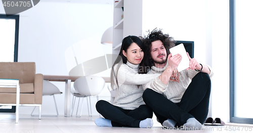 Image of Young Couple using digital tablet on the floor