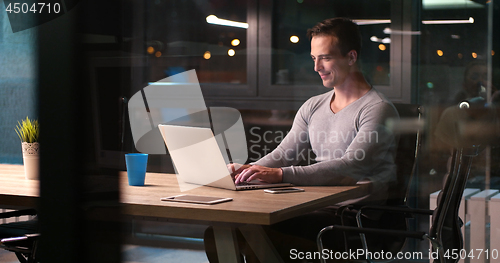 Image of man working on laptop in dark office