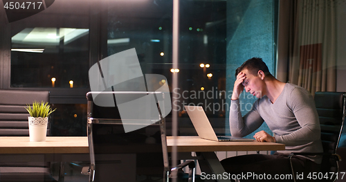 Image of man working on laptop in dark office