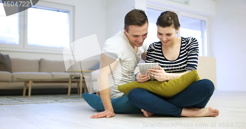 Image of Young Couple using digital tablet on the floor