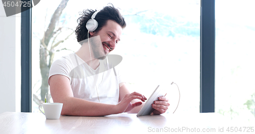 Image of young man listenig music on tablet at home