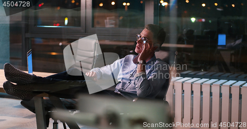 Image of businessman sitting with legs on desk at office