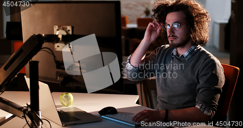 Image of man working on computer in dark office