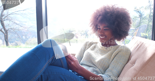 Image of african american woman at home using digital tablet