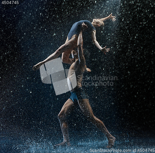 Image of Young couple of ballet dancers dancing unde rwater drops