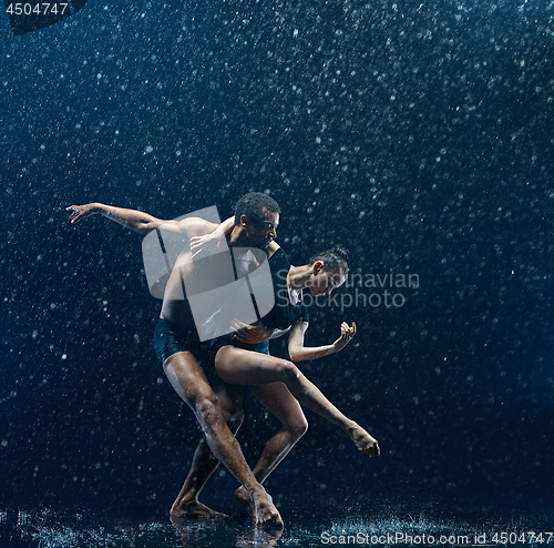 Image of Young couple of ballet dancers dancing unde rwater drops