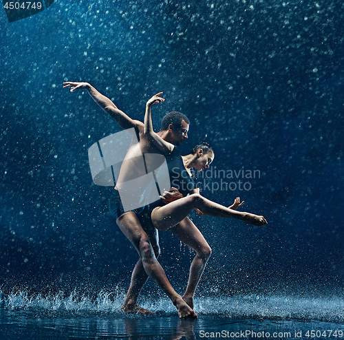 Image of Young couple of ballet dancers dancing unde rwater drops