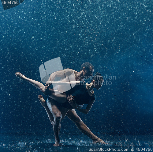 Image of Young couple of ballet dancers dancing unde rwater drops