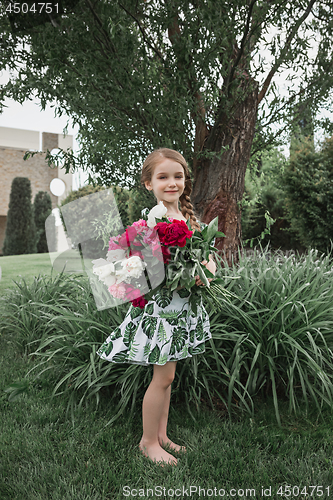 Image of Portrait of smiling beautiful teenage with bouquet of daisies, against green of summer park.