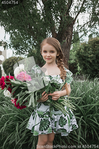 Image of Portrait of smiling beautiful teenage with bouquet of daisies, against green of summer park.