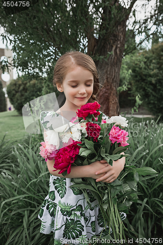 Image of Portrait of smiling beautiful teenage with bouquet of daisies, against green of summer park.