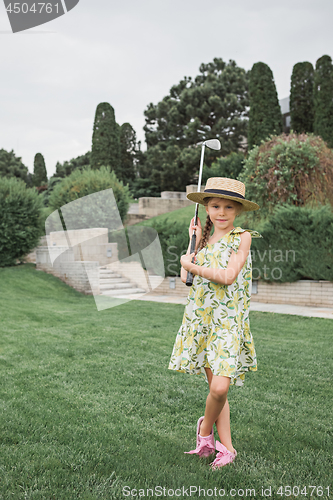 Image of Little girl just swing golf ball on golf course fairway