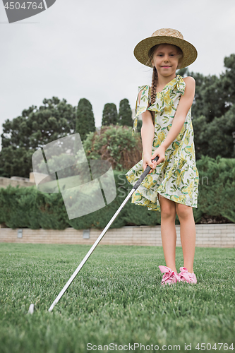 Image of Little girl just swing golf ball on golf course fairway