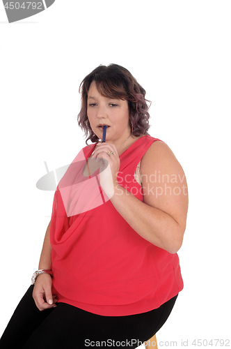 Image of Heavy woman sitting with pen in mouth