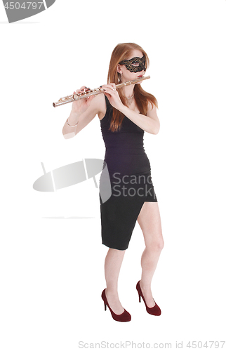 Image of Woman standing, playing the flute wearing a mask