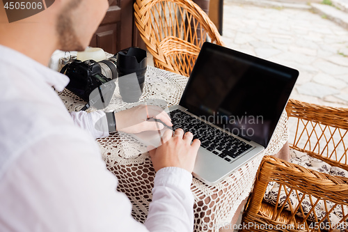 Image of man working with laptop computer and sitting on sofa