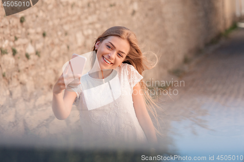 Image of Girl take selfie from hands with phone on summer city