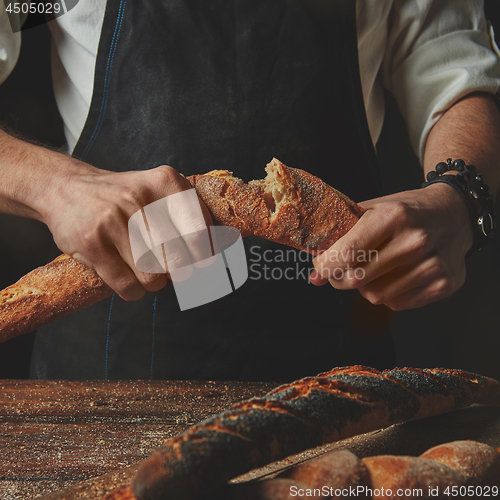 Image of Male hands break the baguette