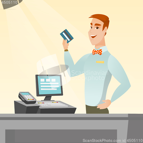 Image of Caucasian cashier holding a credit card.