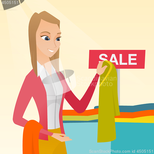 Image of Young woman choosing clothes in the shop on sale.