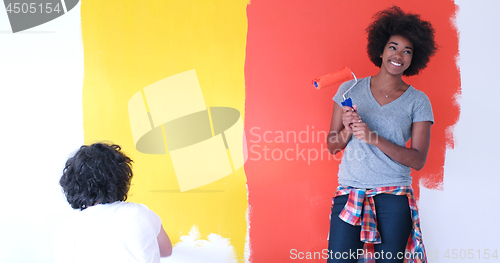 Image of multiethnic couple painting interior wall
