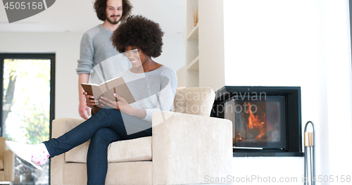 Image of multiethnic couple hugging in front of fireplace